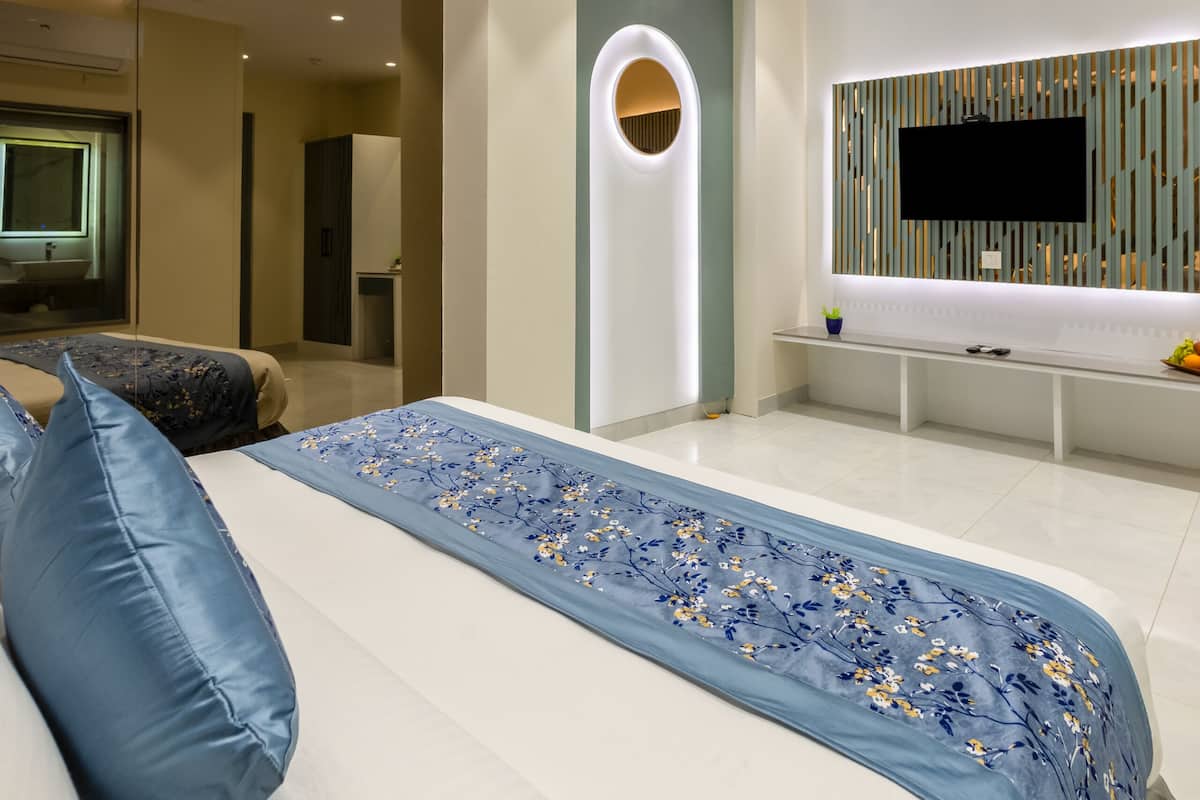 A modern bedroom with a bed, a TV, and a ceiling fan.