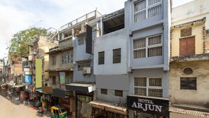 Un edificio de varios pisos con un letrero que dice 'Hotel Arjun' en la planta baja.