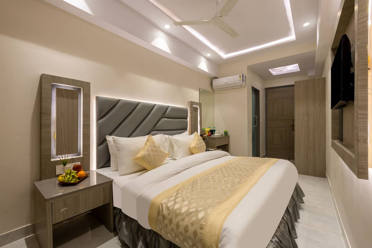 A modern bedroom with a large bed, bedside tables, a mirror, and a ceiling fan.