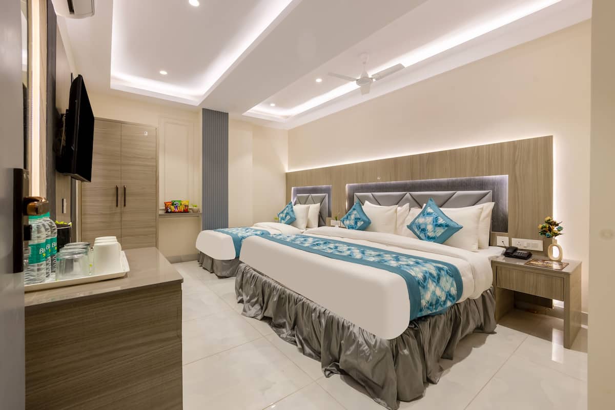A modern hotel room with a large bed, bedside tables, a TV, and a bathroom with a mirror and cabinets.