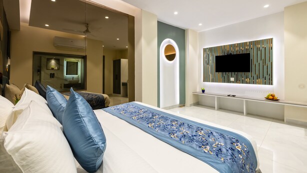 Un dormitorio moderno con una cama grande, un televisor montado en la pared y un ventilador de techo.