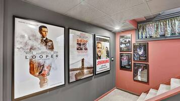 A hallway with framed movie posters on the wall, a staircase, and a window with patterned curtains.