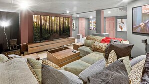 Een moderne woonkamer met een grote flatscreen televisie, een houten salontafel en een zithoek.