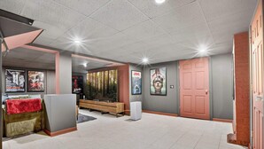 Een ruime kamer met een grote flatscreen-tv, een houten bank en een roze deur.