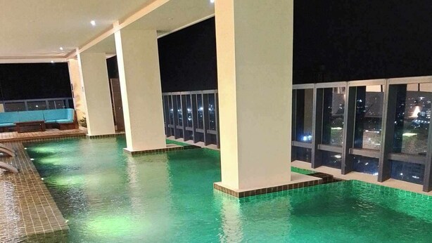 An indoor swimming pool with clear water, surrounded by white pillars and glass windows. - The City Escape: Stylish Condo Near Ayala Bloc & IT Park (Cebu City)