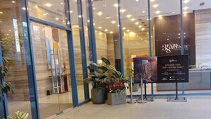 A modern hotel entrance with glass doors, potted plants, and a signboard. - The City Escape: Stylish Condo Near Ayala Bloc & IT Park (Cebu City)