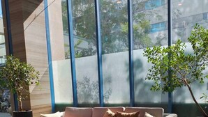 A modern living room with a beige sofa, a wooden coffee table, and two potted plants. - The City Escape: Stylish Condo Near Ayala Bloc & IT Park (Cebu City)