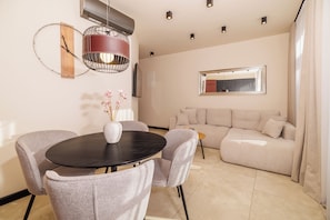 A modern living room with a round dining table, grey upholstered chairs, a beige sofa, and a large mirror on the wall. - Vacation apartment in the center of Crikvenica (Crikvenica)