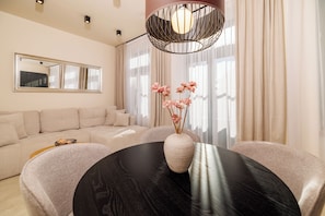 A modern living room with a round dining table, a sofa, a vase with flowers, and a large mirror. - Vacation apartment in the center of Crikvenica (Crikvenica)
