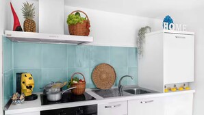 Una cocina con encimera blanca, estufa, pileta y alacena blanca.