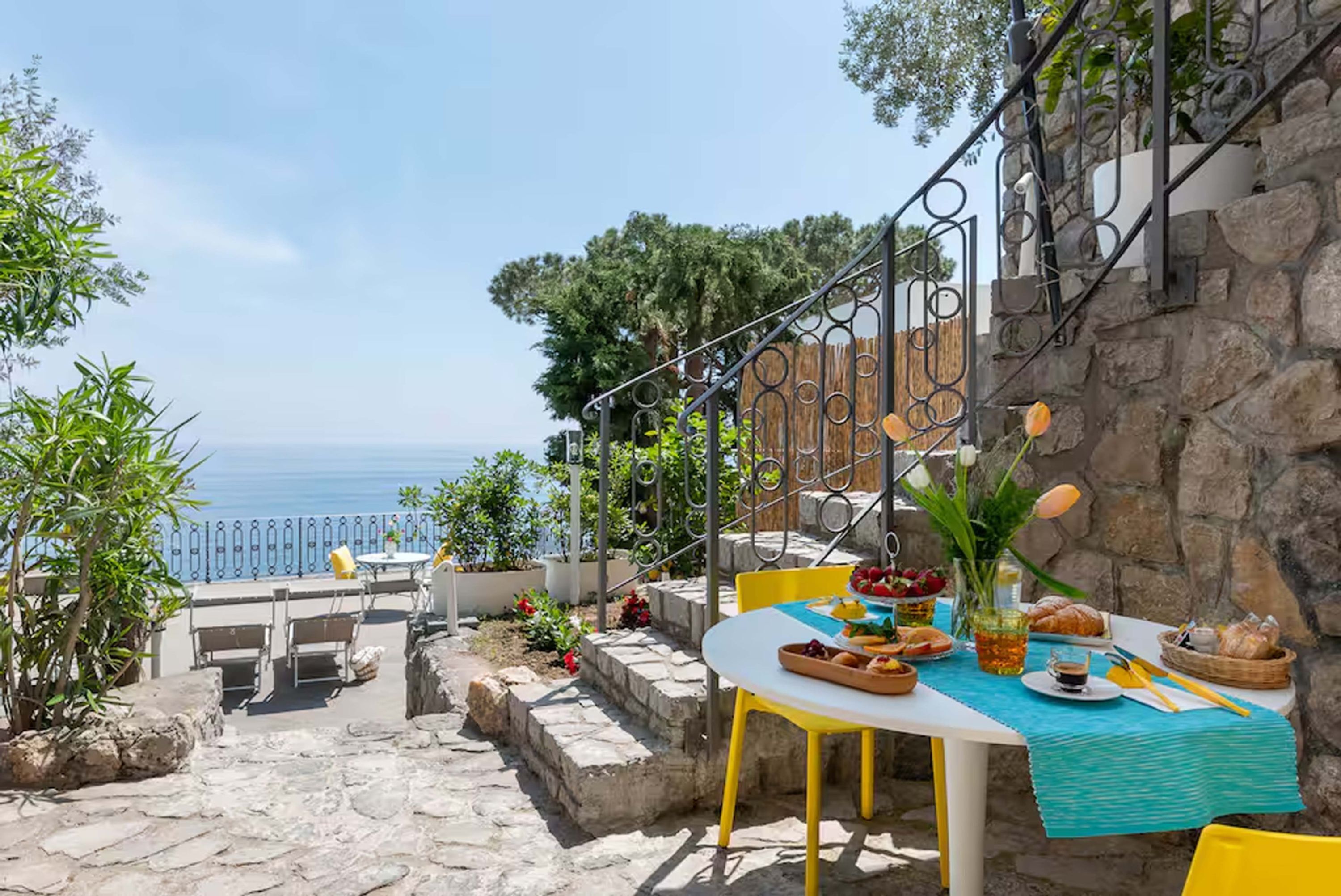 Eine Terrasse mit Esstisch, mit Blick auf eine schöne Meerlandschaft.