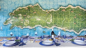 Una mesa de comedor con platos, vasos y cubiertos, con una pared de mosaicos al fondo.