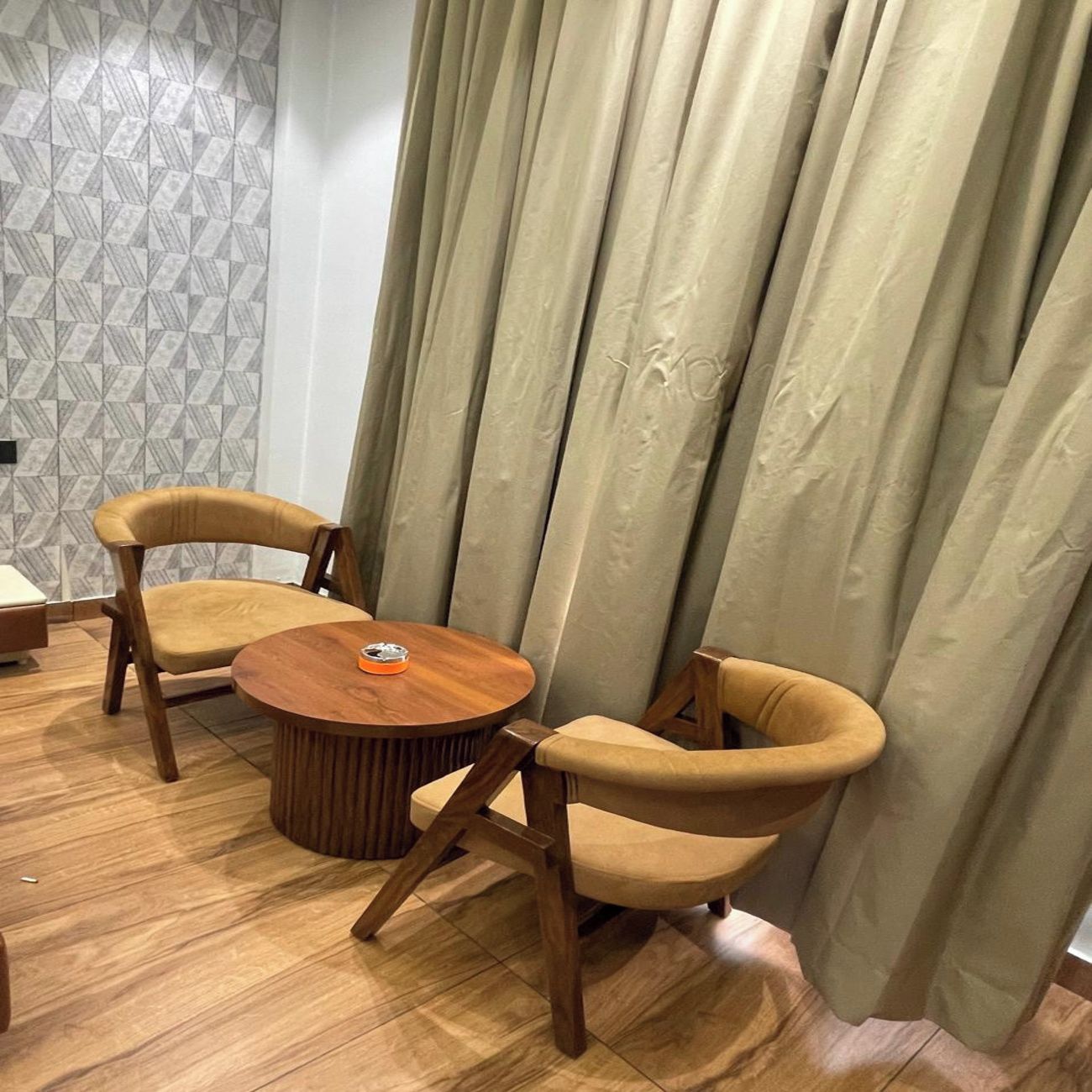A room with a round wooden table, two armchairs, and a patterned wall.