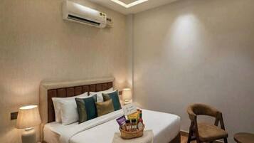 Una habitación de hotel con cama, lámparas de noche, ventilador de techo y aire acondicionado.