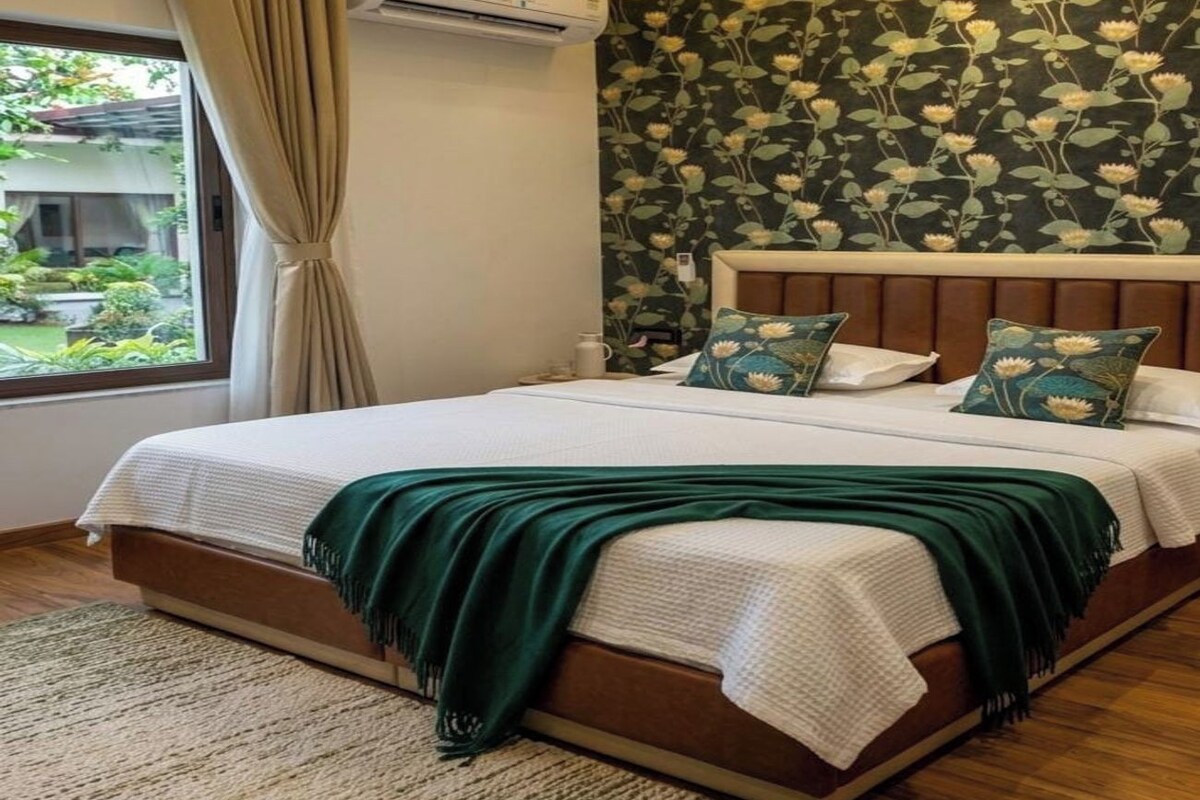 A modern bedroom with a large bed, a headboard with a floral wallpaper, and a window with curtains.