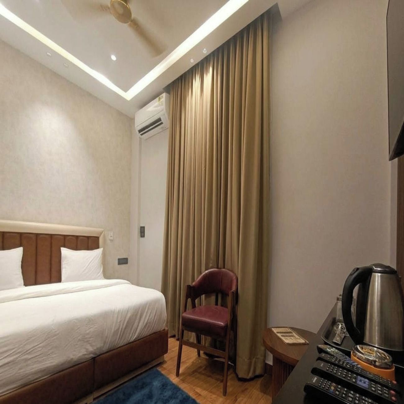 A hotel room with a bed, a chair, a coffee maker, and a desk with a telephone.