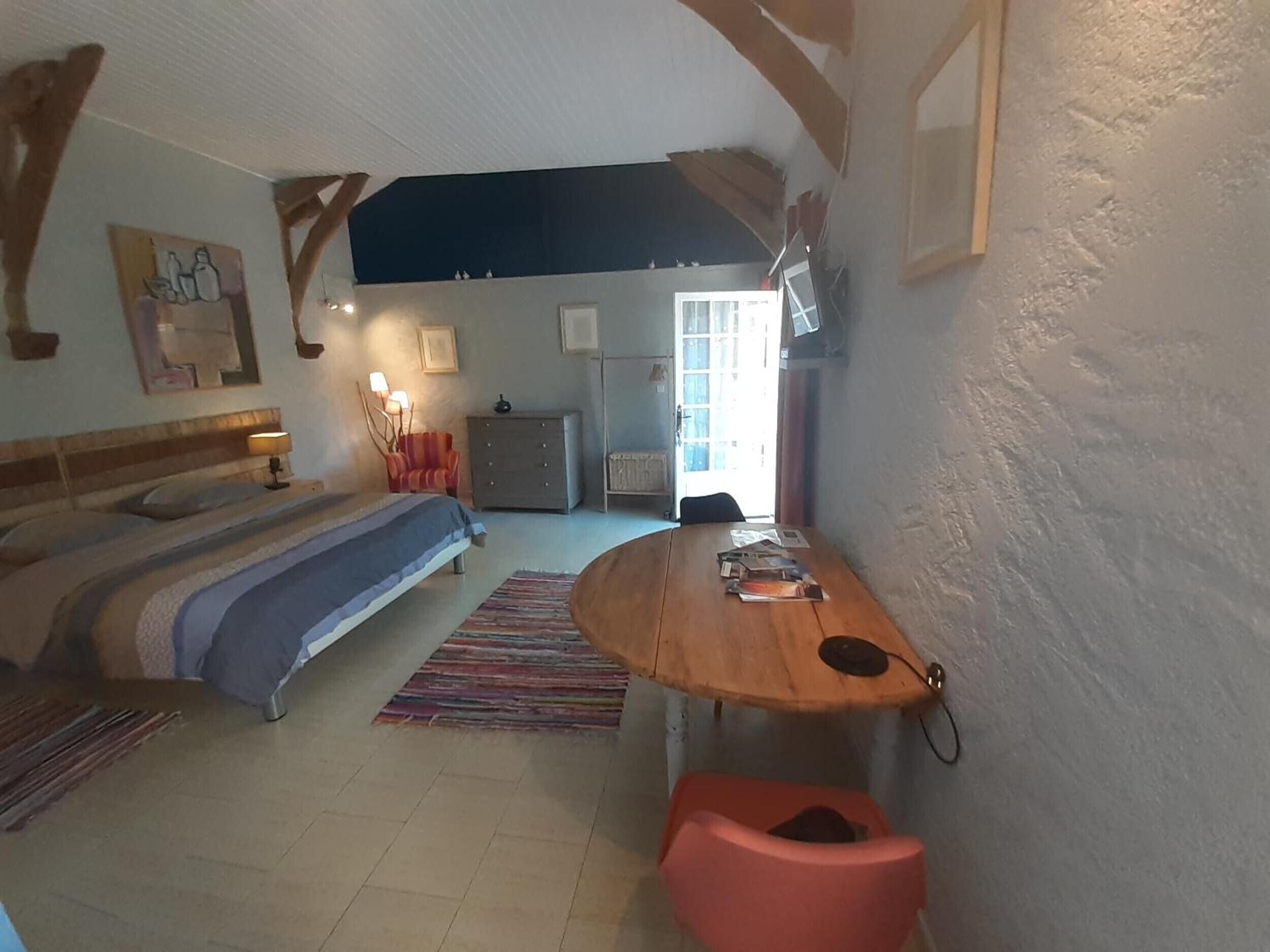 Een slaapkamer met een bed, een bureau, een stoel, een kast en een raam.