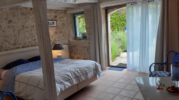 Ein Zimmer mit einem Bett, einem Tisch mit einem Glas und Blick auf Grün.