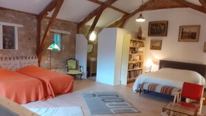 Ein gemütliches Zimmer mit einem Bett, einem Sofa, einem Sessel, einem kleinen Tisch und einem Bücherregal.