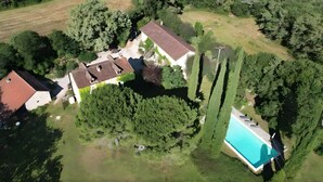 Eine Luftaufnahme eines Grundstücks mit Schwimmbad, großem Haus und umliegender Bepflanzung.