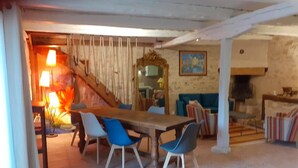 Ein Essbereich mit Holztisch und blauen Stühlen, eine Treppe und eine Küchenzeile mit Herd.