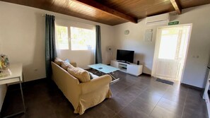 Ein Wohnzimmer mit einer Couch, einem Fernseher und einem Fenster mit Vorhängen.