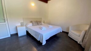 Ein Schlafzimmer mit einem Bett, Nachttischen, einem Sessel und einer Wandleuchte.
