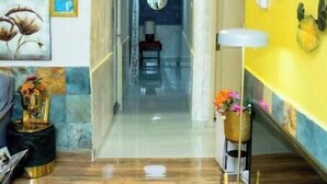 Un intérieur moderne avec un couloir menant à une pièce, un grand luminaire suspendu et des œuvres d’art murales.