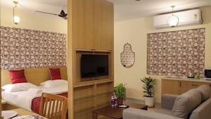 Ein Hotelzimmer mit Bett, Fernseher, Küchenzeile, Essbereich und Deckenventilator.