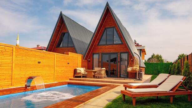 Una casa moderna con piscina, dos sillones de descanso y un patio.