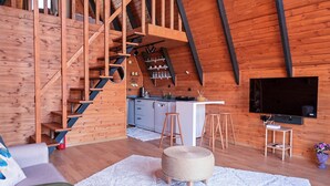 Interior de madera con una escalera, kitchenette y un televisor de pantalla plana.