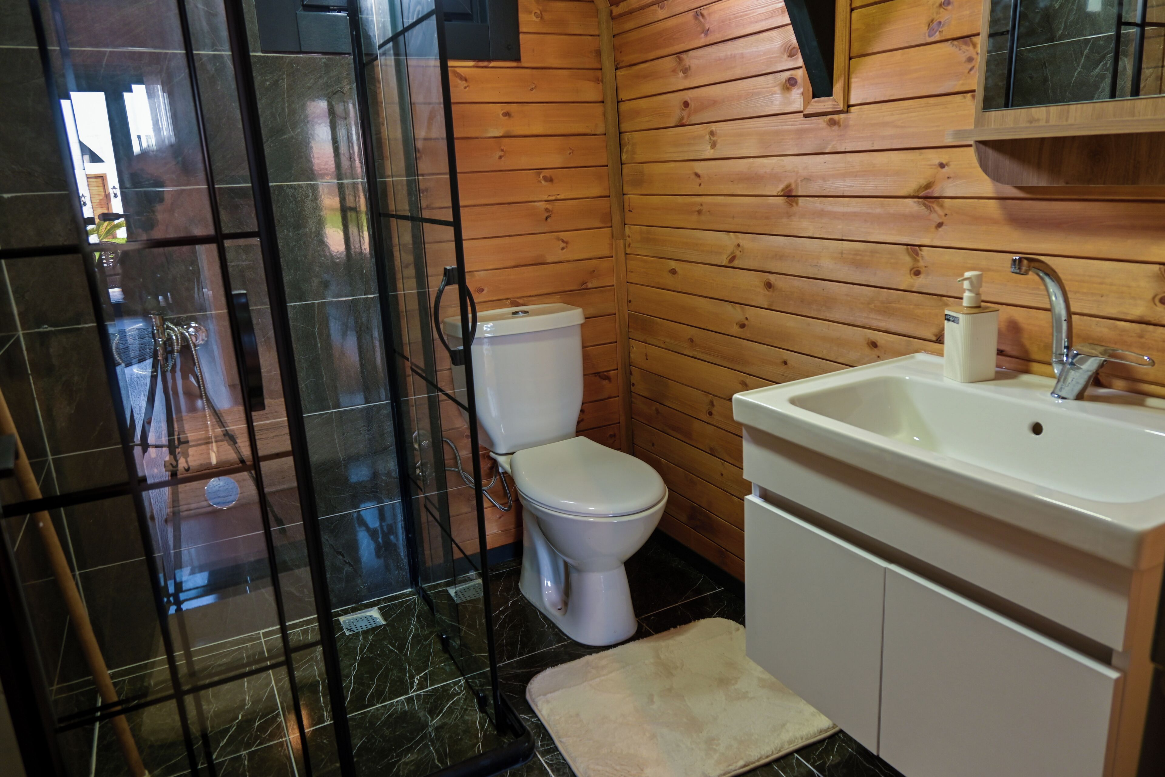A bathroom with a toilet, sink, and shower area.