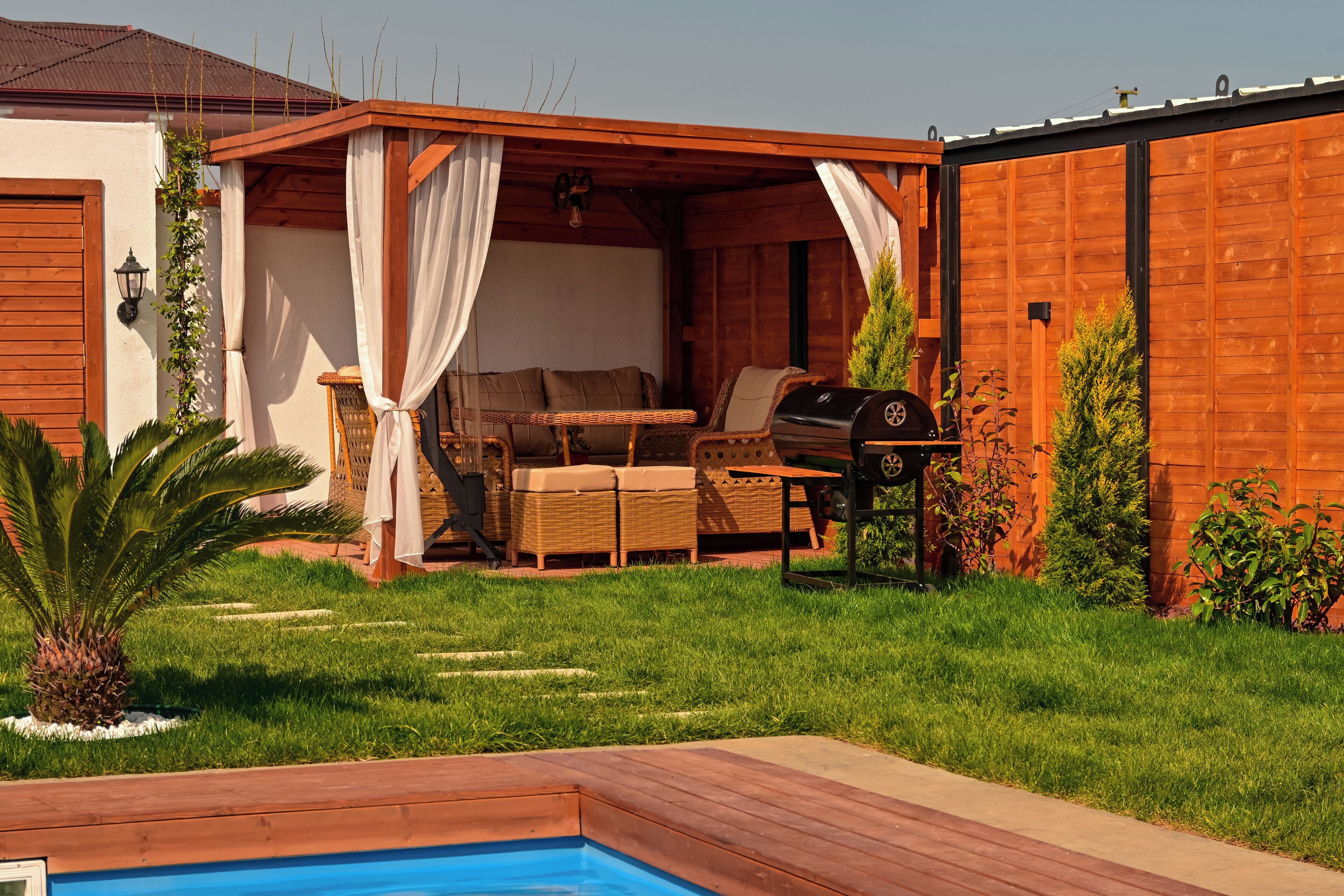 A wooden deck with outdoor furniture, a barbecue grill, and a swimming pool.
