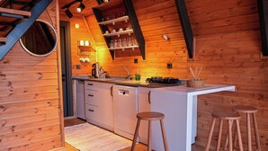 Un interior de madera con una isla de cocina, taburetes y un espejo circular.