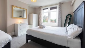 A bedroom with a bed, a dresser, a mirror, and a window with curtains. - Cosy Home 7 Minutes From Newcastle City Centre (Gateshead)