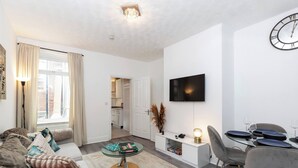A modern living room with a sofa, coffee table, dining table, and TV. - Cosy Home 7 Minutes From Newcastle City Centre (Gateshead)