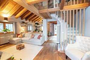 A spacious living area with a white sofa, a wooden coffee table, and a staircase leading to an upper level.