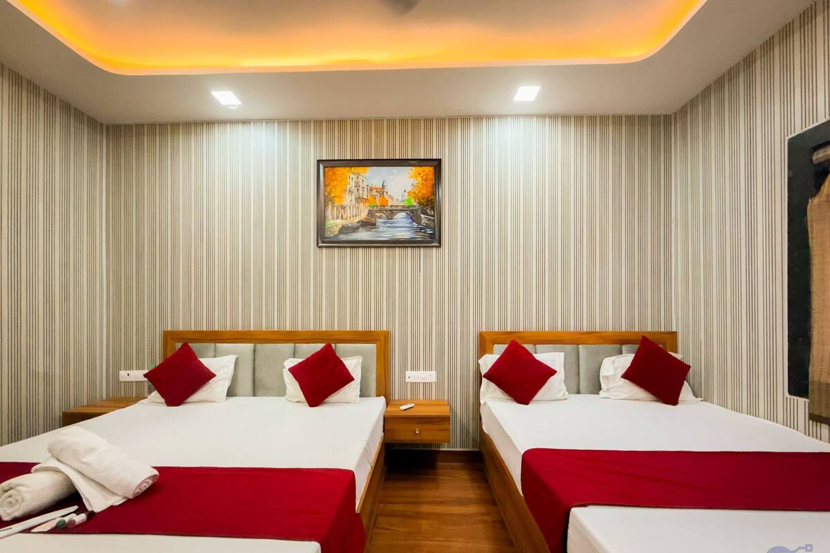 A hotel room with two beds, striped wallpaper, a painting, and a wooden floor.