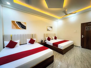 Ein Hotelzimmer mit zwei Betten, einem Deckenventilator und Kunstwerken an den Wänden.