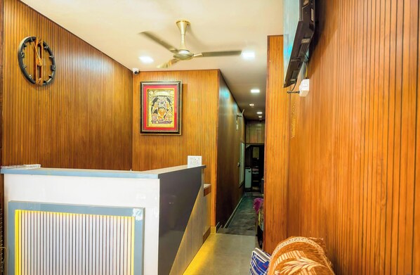 Ein Hotelgang mit Holzvertäfelung, einer Rezeption, einem Deckenventilator und einem gerahmten Bild an der Wand.