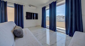 Ein Hotelzimmer mit Bett, Fernseher und Blick auf die Stadt durch große Fenster.