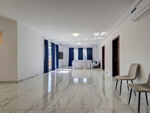Ein geräumiges Zimmer mit Marmorboden, einem Bett, einer Couch und zwei Stühlen.