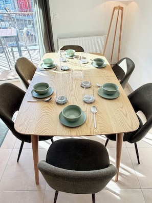 A dining table set with green plates, glasses, and cutlery, surrounded by chairs. - Cimes B202 by Avecoeur (Briançon)