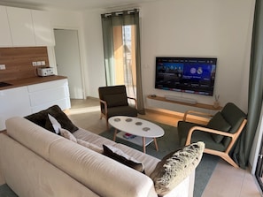 A modern living room with a sofa, chairs, a coffee table, and a TV displaying sports content. - Cimes B202 by Avecoeur (Briançon)