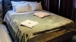 Une chambre à coucher avec un lit, un tableau encadré au mur et une fenêtre avec des rideaux.