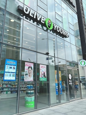 A modern building with a large glass facade, a prominent 'OLIVE YOUNG' sign, and various advertisements on the windows. - 5 min to Subway/Airport BusPrivateRoom 20 min to Hongdae MyeongdongNearHan River (Seoul)