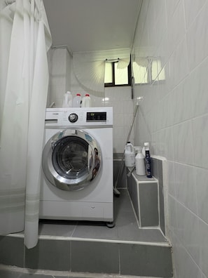 A compact laundry room with a front-loading washing machine, a drying rack, and a few bottles of detergent. - 5 min to Subway/Airport BusPrivateRoom 20 min to Hongdae MyeongdongNearHan River (Seoul)