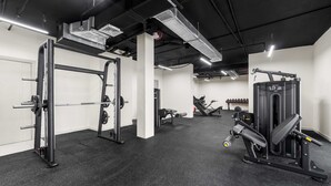 A gym with weightlifting equipment, a bench press, and a squat rack. - Free Housekeeping Visits During Your Stay - Stayshort - Peaceful Studio in Jebel Ali That Sleeps 2 (Dubai)