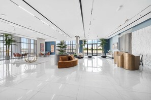 Eine großzügige Lobby mit modernem Design, inklusive einer großen Sitzecke, einem Empfangsbereich und großen Fenstern.