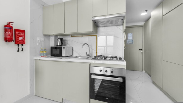 A modern kitchen with a microwave, stove, oven, and a fire extinguisher. - Free Housekeeping Visits During Your Stay - Stayshort - Peaceful Studio in Jebel Ali That Sleeps 2 (Dubai)